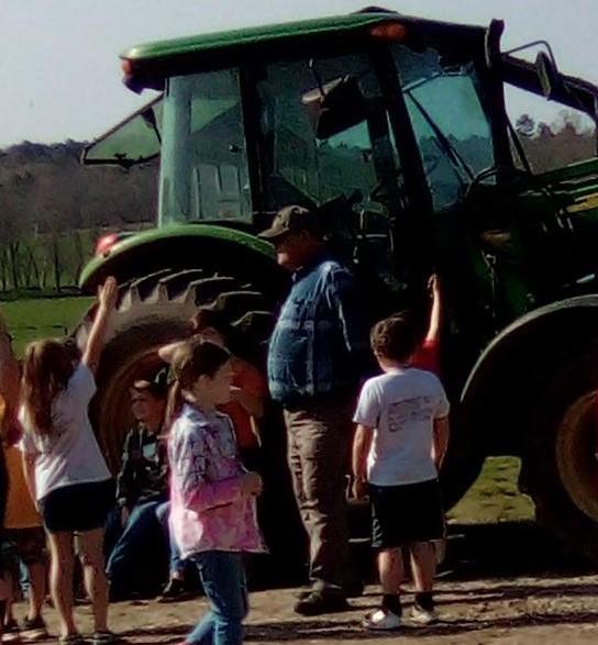 Presenter and a couple of 2nd graders looking at a tractor at Ag Day 22 